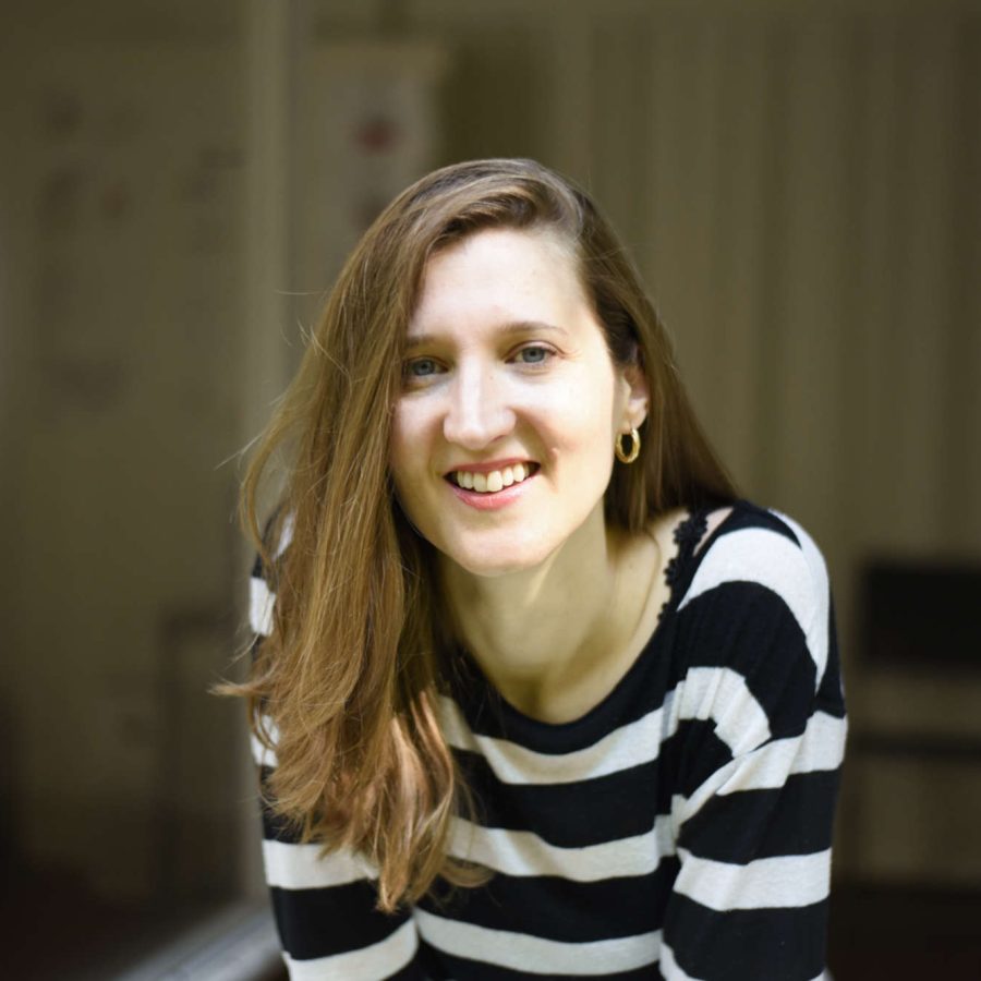 Martina Rick, Vocal und Performance Coach, schaut im schwarz-weiss-gestreiften Shirt lächelnd aus dem offenen Fenster ihres Studios in Basel