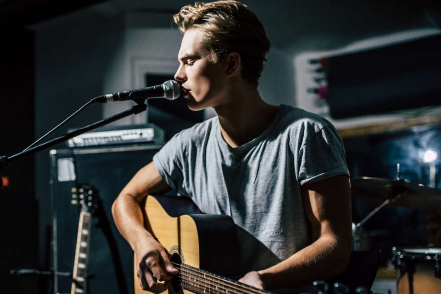 junger Sänger im Probestudio singend an der Gitarre
